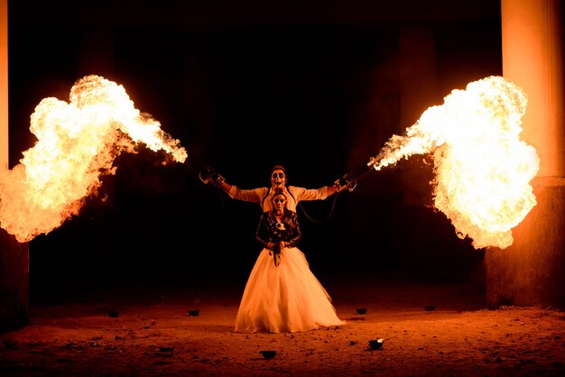 halloween-couple-standing-with-flamethrower-hands-big-fire_104603-1675