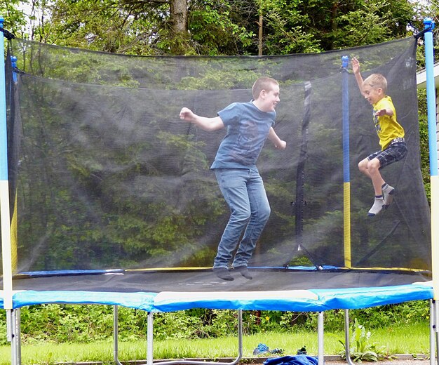 happy-siblings-jumping-trampoline-yard_1048944-5888911